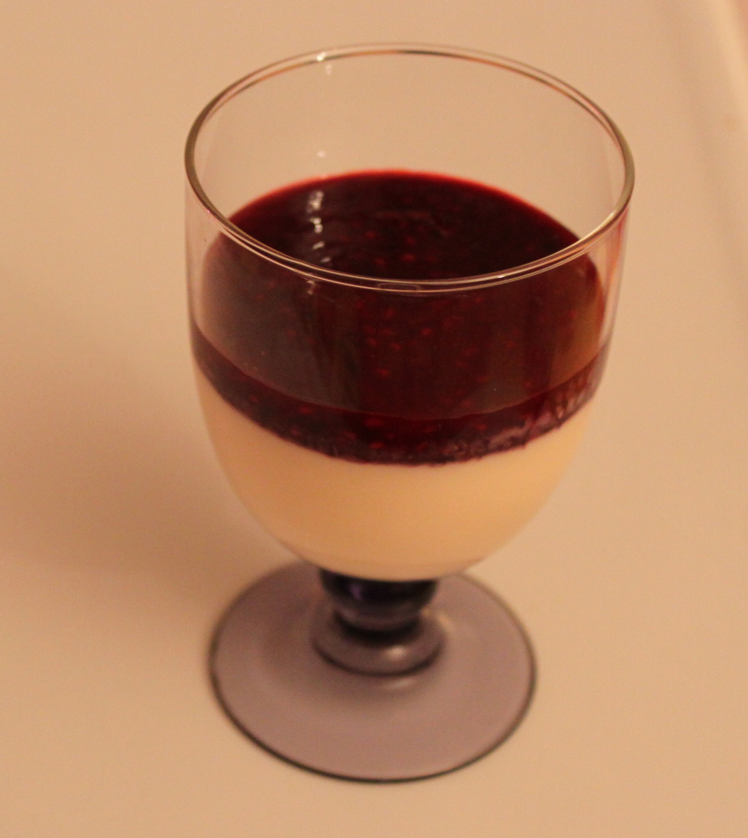 Une panna cotta au coulis de fruits rouges servie dans un verre